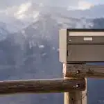 black and gray box on brown wooden fence